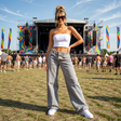 Woman posing at a music festival with colorful flags and stage in the background