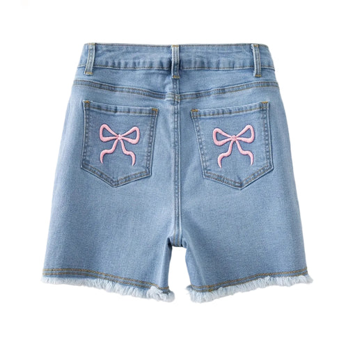 Denim shorts with pink bows on the back pockets against a light background