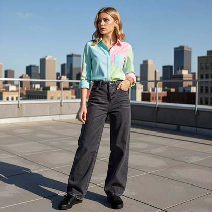 Woman wearing a colorful shirt and black jeans on a rooftop with city skyline in the background