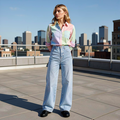 Woman wearing a colorful shirt and light blue jeans on a rooftop with city skyline in the background