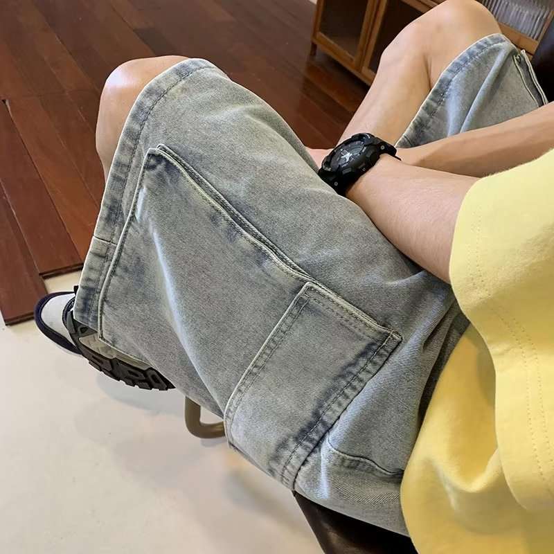 Person wearing light blue denim shorts sitting on a chair indoors.