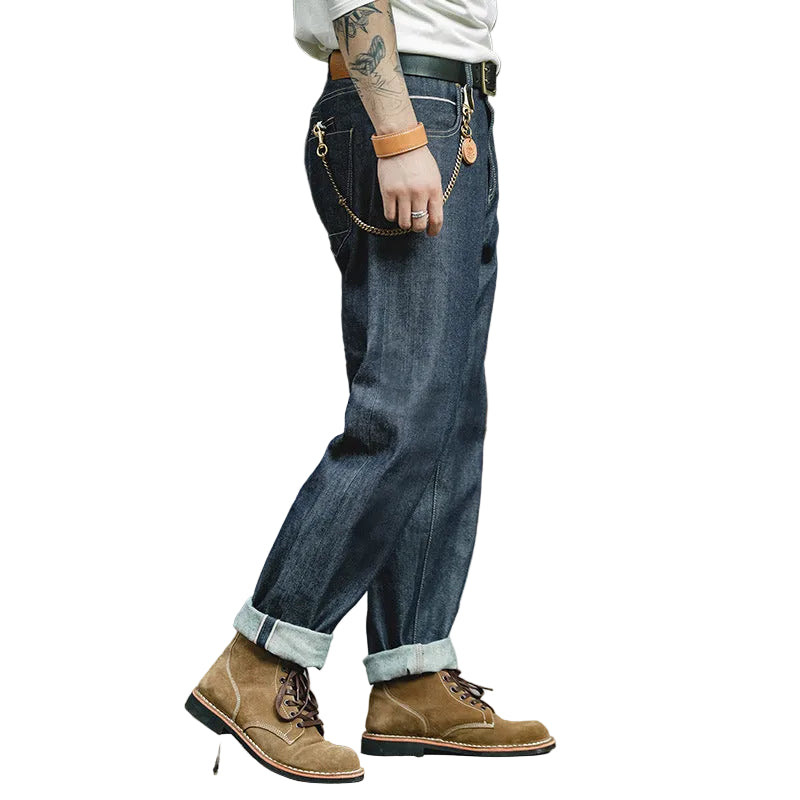 Person wearing blue jeans and brown boots standing in front of a brick wall.