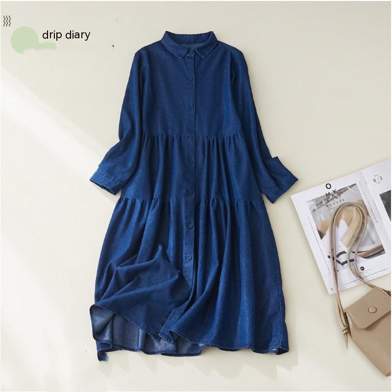 Blue dress on a white background with a beige handbag and magazine.