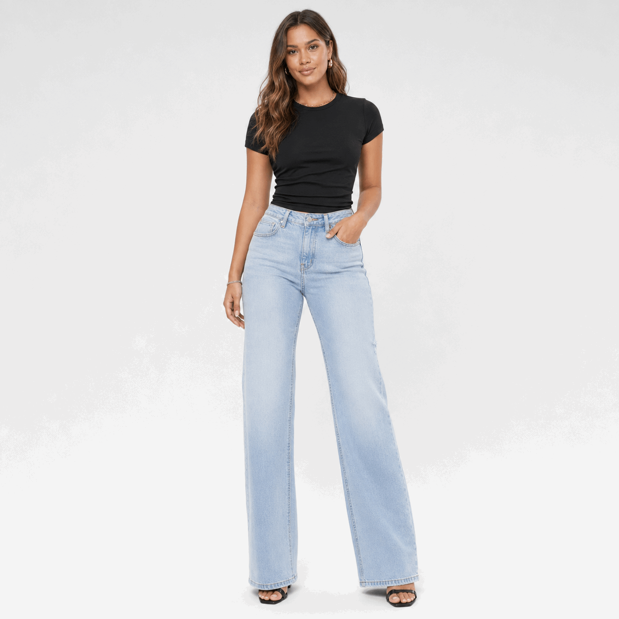Woman wearing light blue jeans and a black top on a white background
